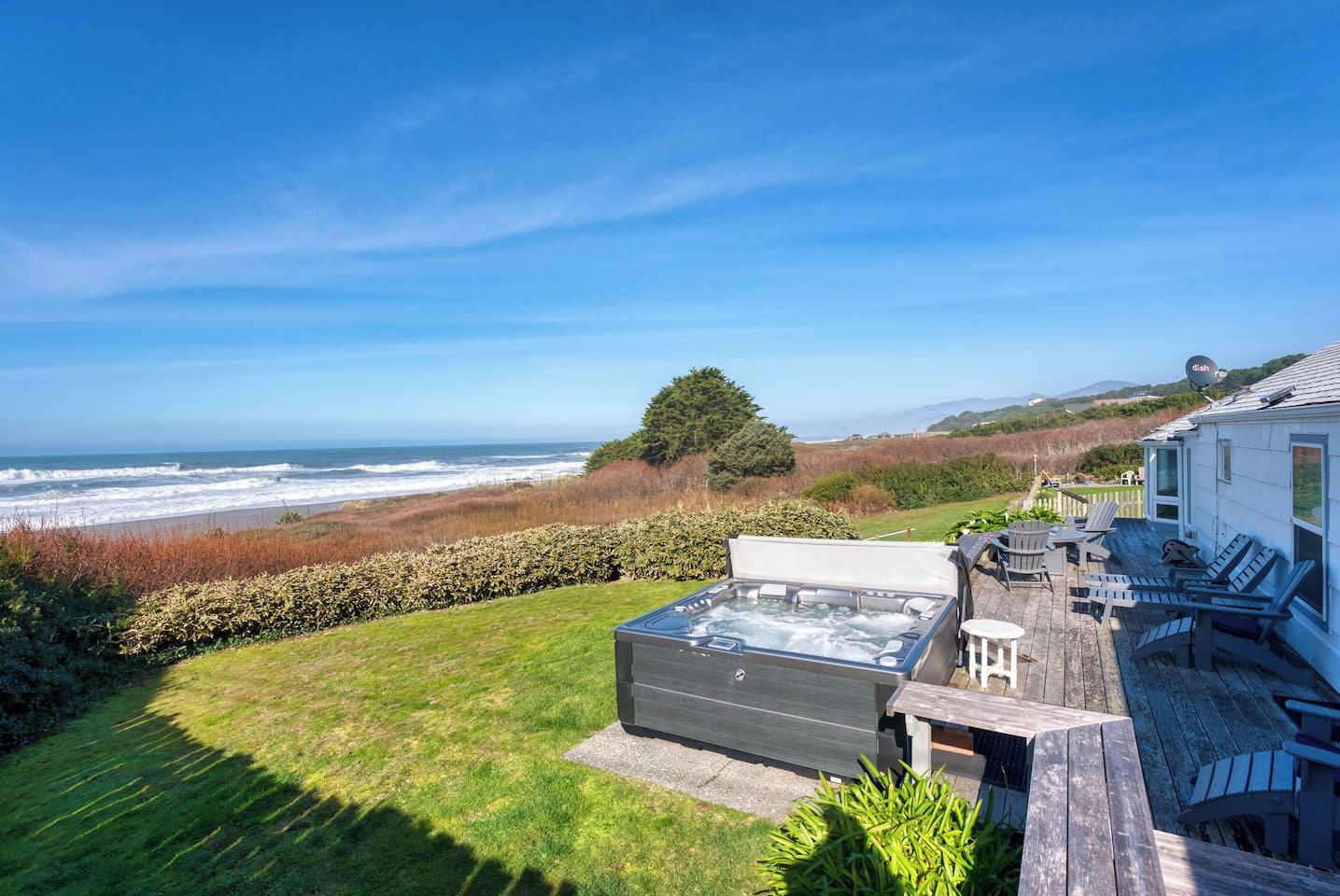 Un jacuzzi en una terraza de madera con vista al océano.