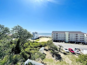 A hotel with a beach view, parking area, and a large building with multiple floors.