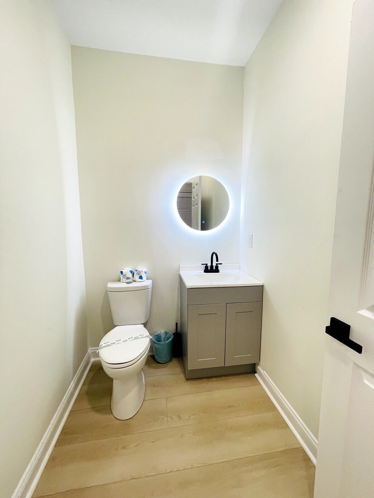Een kleine, schone badkamer met toilet, wastafel en spiegel.