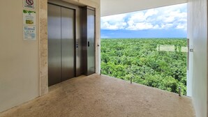 A balcony with a view of a dense green forest and a clear sky. - Private Garden Condo by Concierge4u (Playa del Carmen)