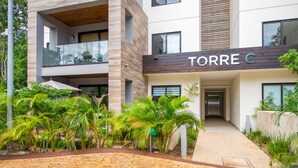 A modern building with a sign reading "TORRE C". - Private Garden Condo by Concierge4u (Playa del Carmen)