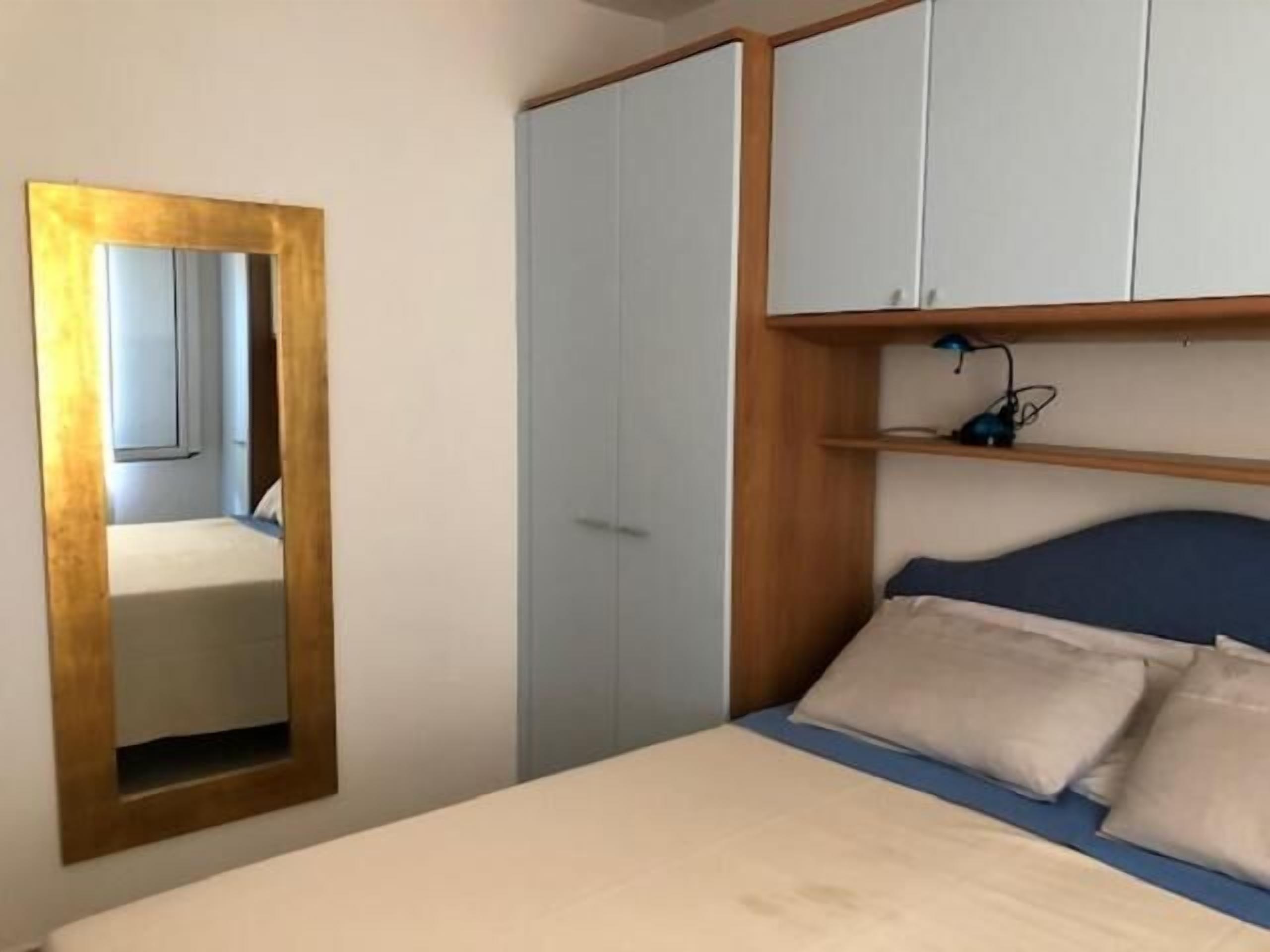 Un dormitorio con cama, armario y espejo.