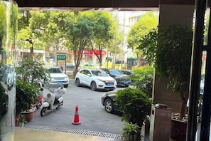 A parking area with cars and a scooter, surrounded by potted plants and trees. - Minhang Hotel (Enshi City)