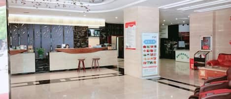 A hotel lobby with a reception desk, seating area, and a large informational poster.