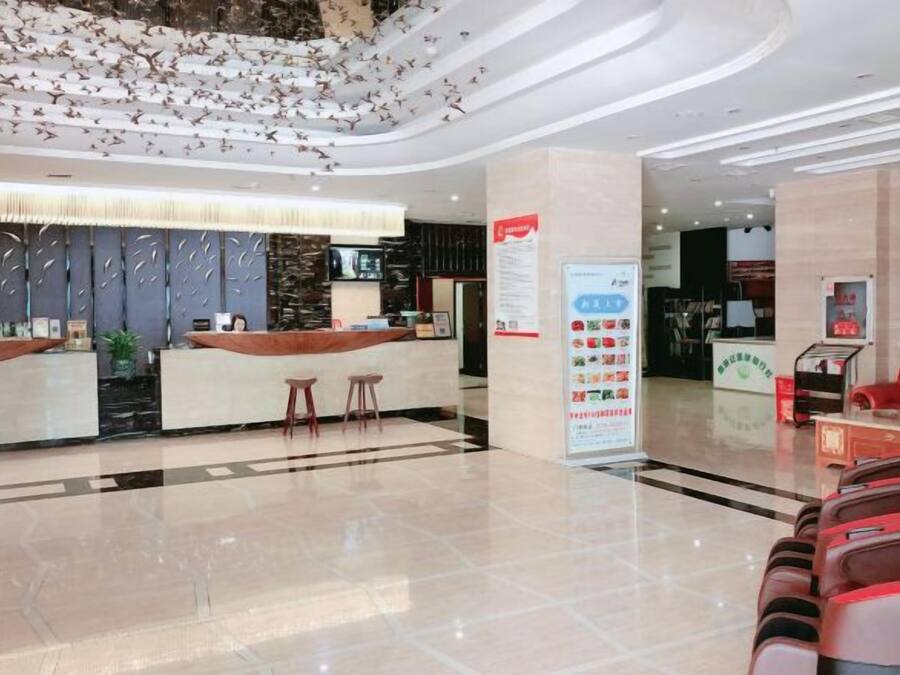 A hotel lobby with a reception desk, seating area, and a large informational poster.