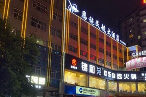 Un edificio de varios pisos con señalización iluminada, una entrada destacada y un letrero visible para un restaurante.