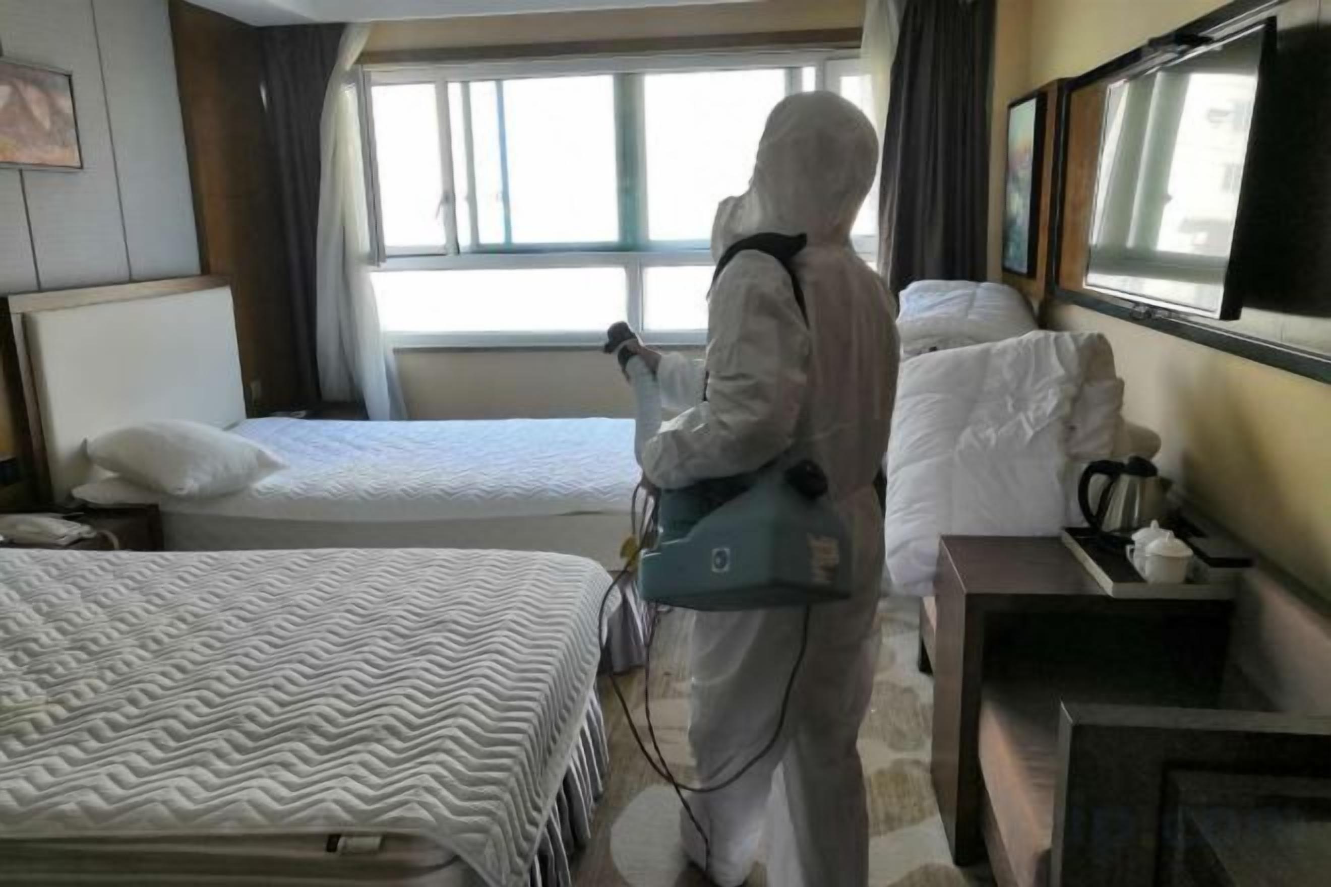 Habitación de hotel con dos camas, una mesita de noche con lámpara y una ventana con cortinas.