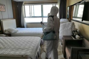 Habitación de hotel con dos camas, una mesita de noche con lámpara y una ventana con cortinas.