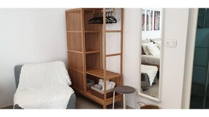 Une pièce comprenant une armoire en bois, un miroir, un canapé gris et une petite table ronde.