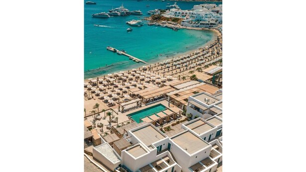 Vue aérienne d’une station balnéaire dotée d’un port de plaisance, d’une plage et d’un espace piscine.