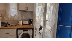 Une cuisine compacte équipée d’un lave-linge, d’une machine à café et d’un grille-pain.