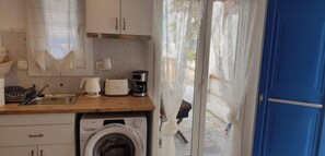 A compact kitchen with a washing machine, a coffee maker, and a toaster.