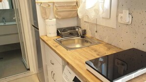 Une cuisine dotée d’un plan de travail en bois, d’un évier en acier inoxydable et d’une plaque de cuisson à induction noire.
