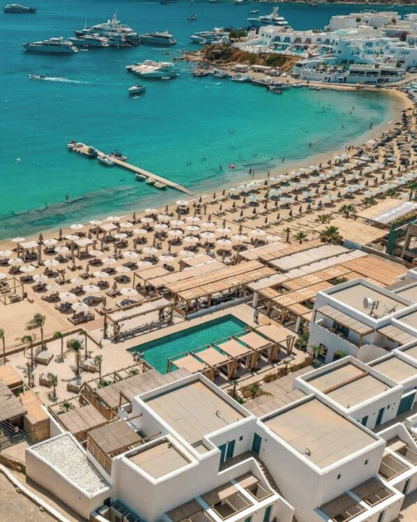 An aerial view of a coastal resort with a marina, beach, and pool area.
