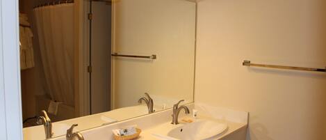 A bathroom with two sinks, a large mirror, and a towel rack.