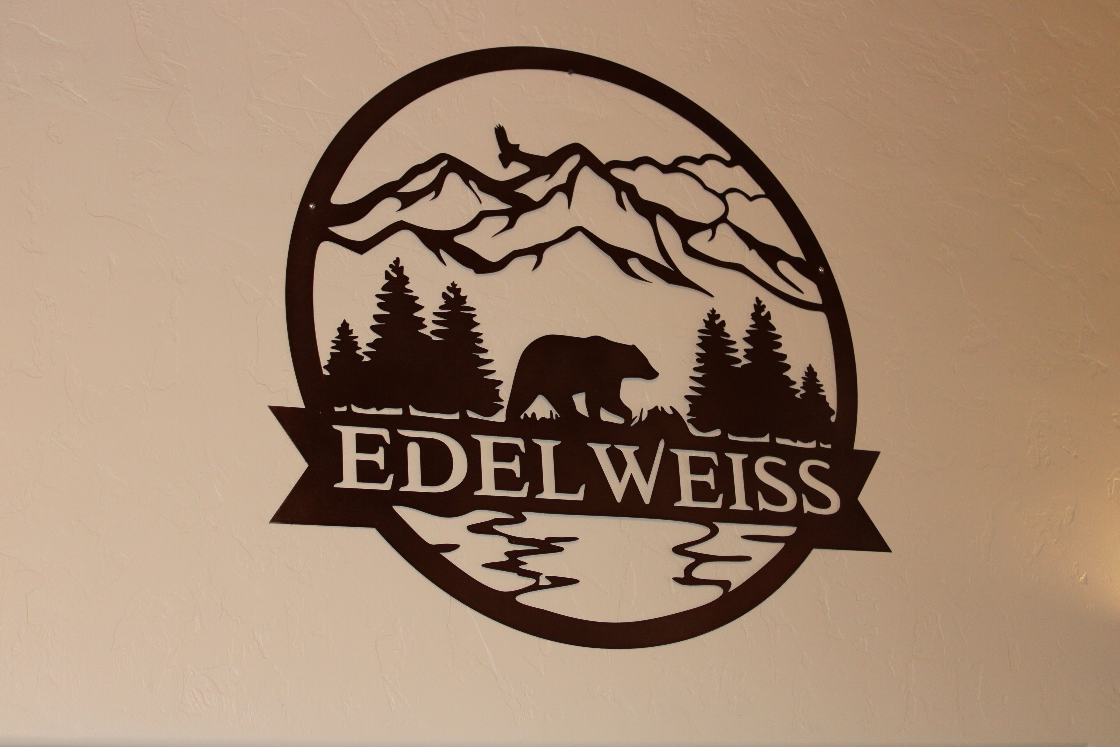 Un adesivo da parete con un paesaggio montano e un orso, con la scritta 'Edelweiss' sotto.