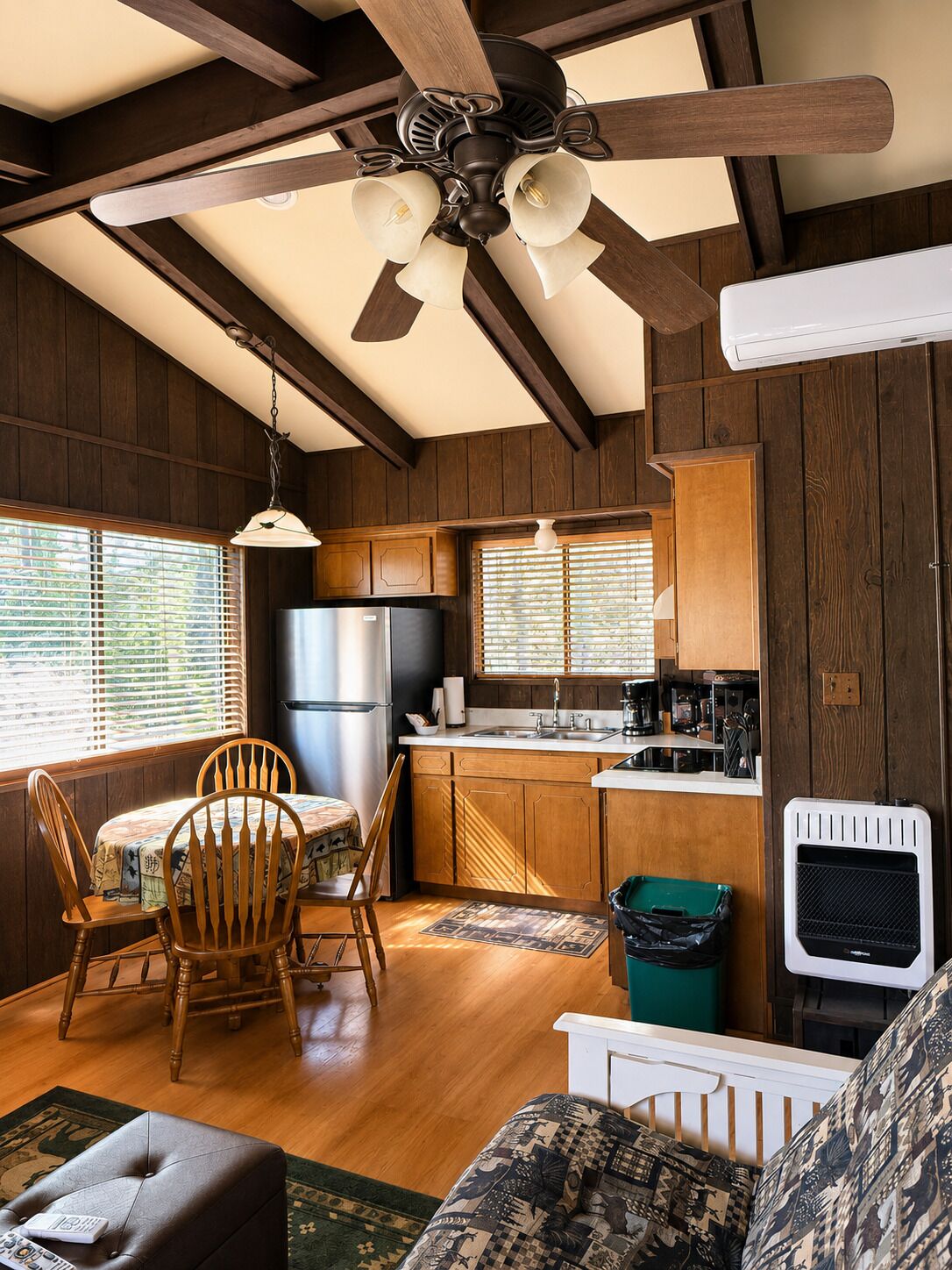 A rustic cabin interior with a dining area, kitchen, and living space.