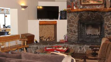A cozy living room with a stone fireplace, a flat-screen TV, and a wooden bench.