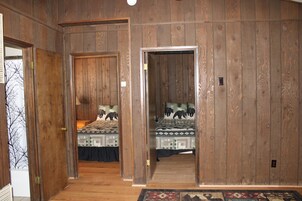 Una habitación con paredes de paneles de madera, dos camas con ropa de cama estampada y una alfombra en el suelo.
