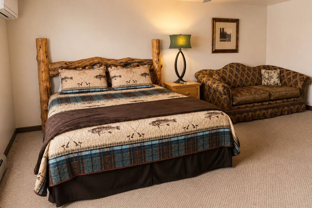 A bedroom with a bed, a chair, a lamp, and a ceiling fan.