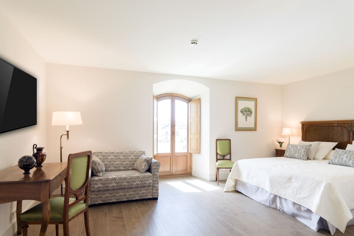 Quarto de hotel com cama, sofá, escrivaninha e cadeira.