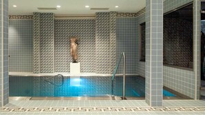 Una piscina interior moderna con un diseño geométrico de azulejos en paredes y suelo.
