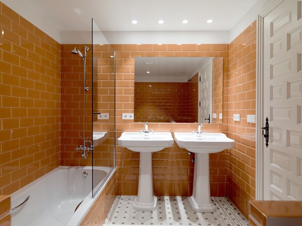 A bathroom with two sinks, a bathtub, and a glass shower enclosure. - Hospedium Hotel La Lozana (Used)