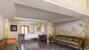 Un dormitorio con cama con dosel, un banco de madera, suelo estampado y un muro decorativo.