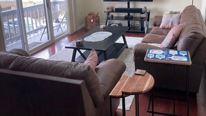 A living room with a sofa, a coffee table, a TV, and a balcony with a view of the street.