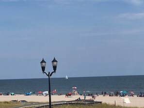 A beach with a clear sky, a sailboat in the distance, and a lifeguard tower. - Beach block - 3 BR/2 bath condo with 2 car parking (Seaside Heights)