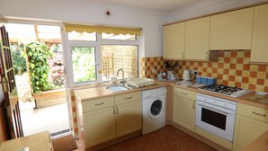 A compact kitchen with a washing machine, oven, and sink.