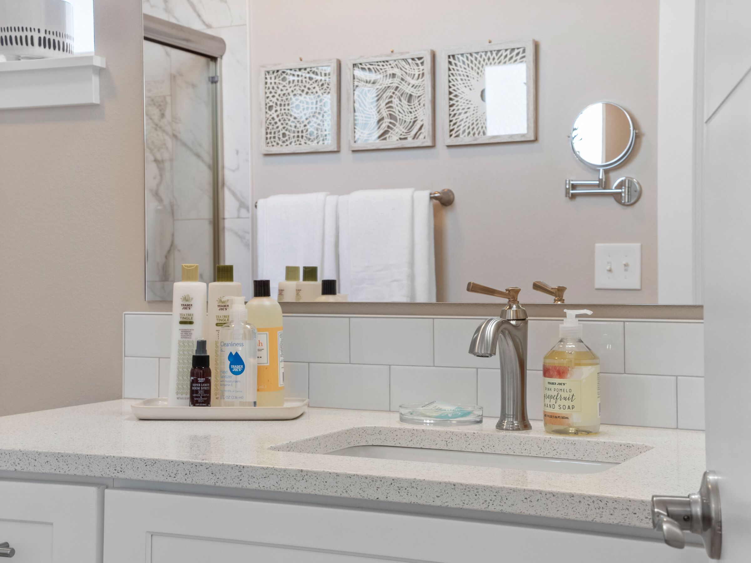 A bathroom with a marble sink, a mirror, and toiletries on the counter.
