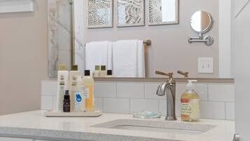 A bathroom with a marble sink, a mirror, and toiletries on the counter.