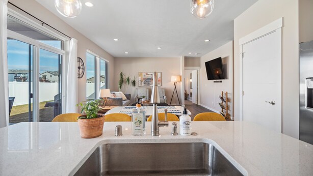 Una cocina moderna con una isla grande, pileta de acero inoxidable y luces colgantes.