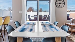 Un salón de conferencias con una gran mesa, sillas, un reloj y vistas a través de un ventanal.