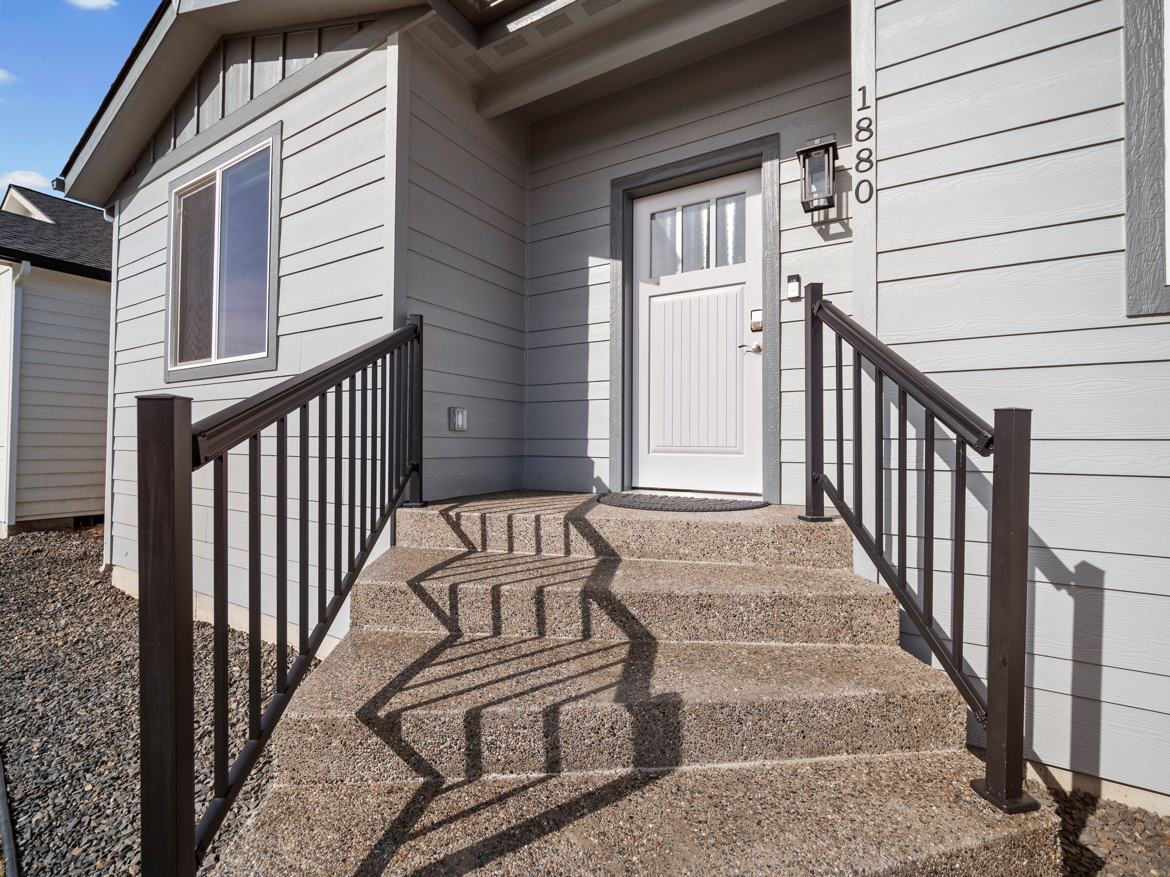 A residential building with a staircase leading to a front door, a mailbox, and a house number.