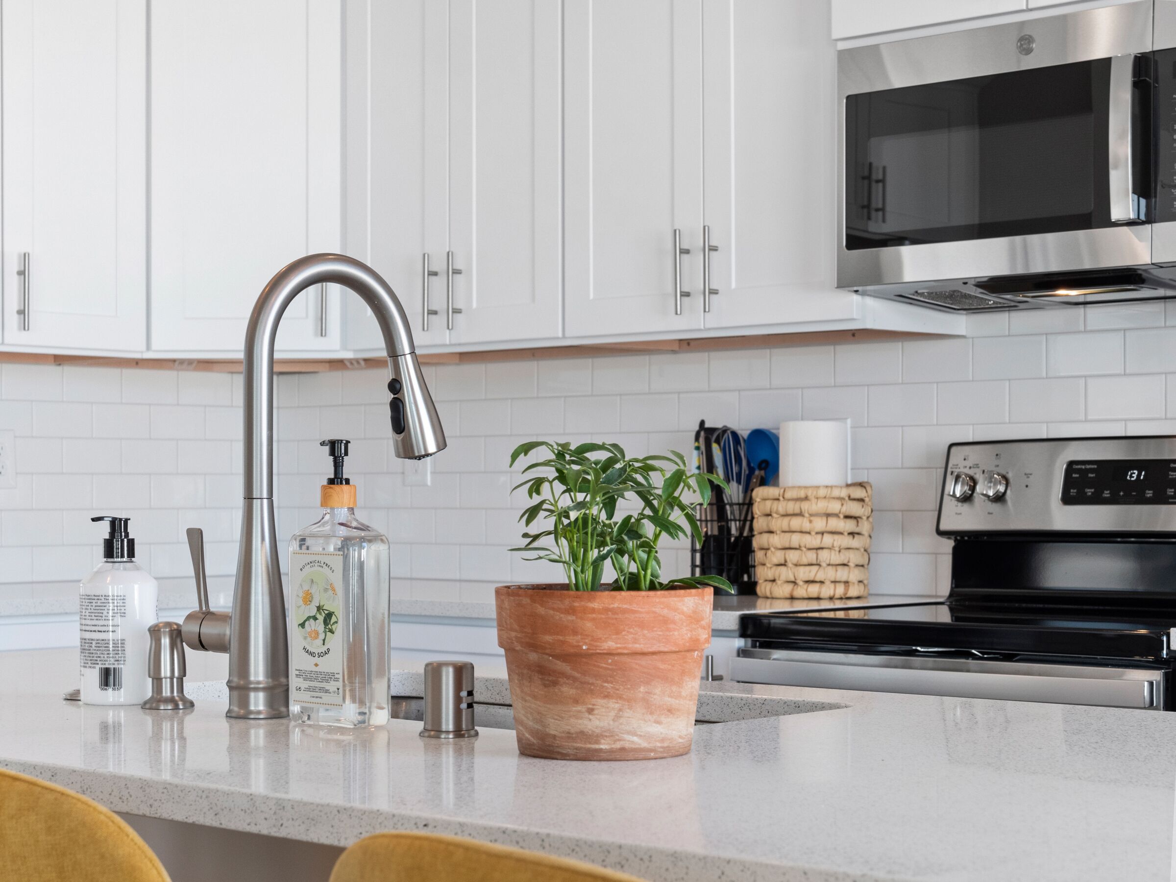 Una cocina moderna con armarios blancos, electrodomésticos de acero inoxidable y una planta en maceta sobre la encimera.