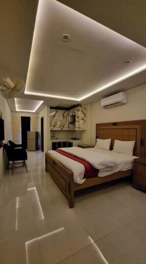 Relax in a spacious room with a large bed, shelving, and a functional desk area.