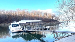 A boat docked at a pier with a covered structure nearby.