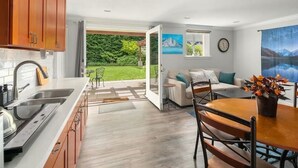 A modern kitchen with wooden cabinets, a built-in oven, and a large window overlooking a garden. - Mountain Themed Suite - Free Parking - Fast WIFI (Seattle)