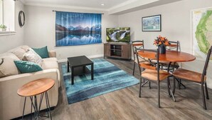 A modern living room with a sofa, coffee table, TV, and dining area with chairs and a table. - Mountain Themed Suite - Free Parking - Fast WIFI (Seattle)