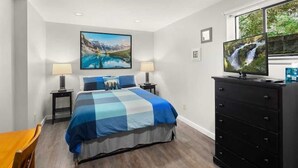 A bedroom with a bed, two bedside tables, a dresser, a TV, and a painting on the wall. - Mountain Themed Suite - Free Parking - Fast WIFI (Seattle)