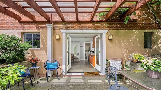 A covered patio with a brick wall, a wooden pergola, and a view into the house. - Mountain Themed Suite - Free Parking - Fast WIFI (Seattle)