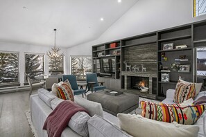 Uma sala de estar moderna com lareira, janelas amplas e um espaço de estar acolhedor.