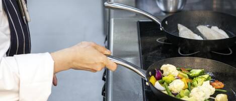A person cooking vegetables in a pan on a stove.