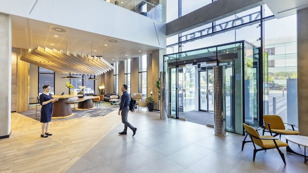 A spacious lobby with a reception desk, seating area, and large windows offering views of the outside. - Novotel Liverpool Paddington Village (Liverpool)