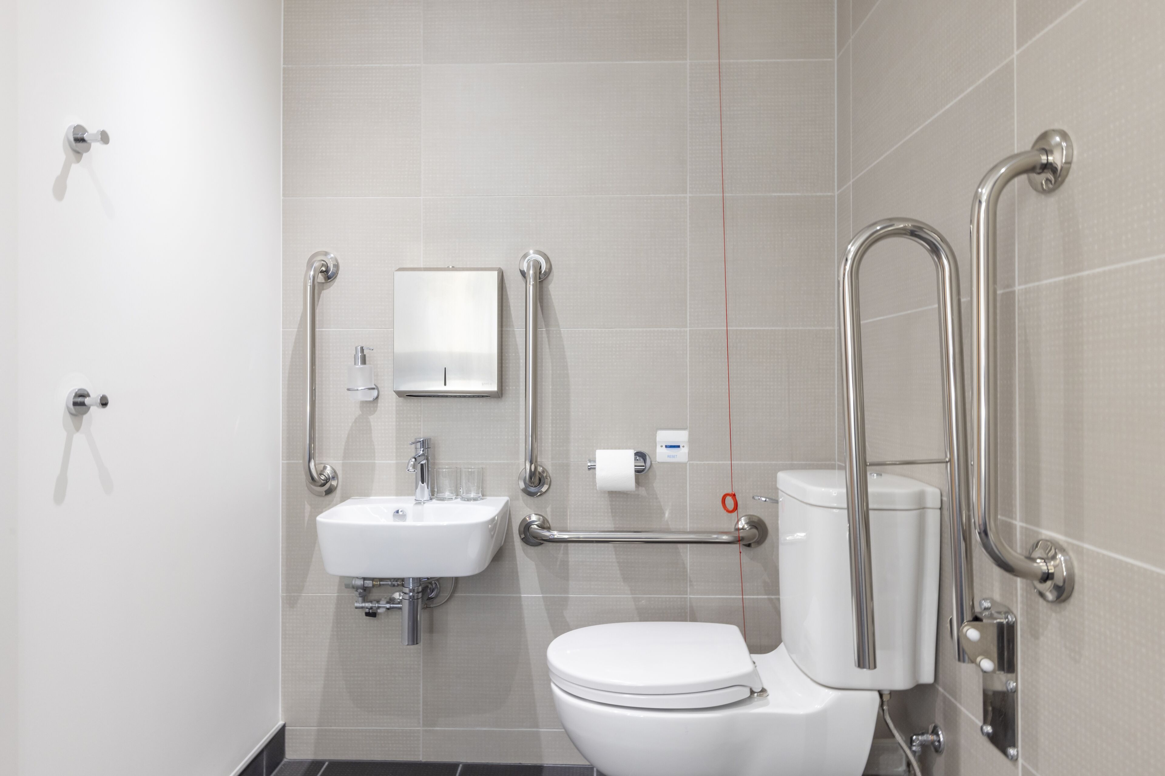Un bagno moderno con lavabo, water e maniglie di sostegno.