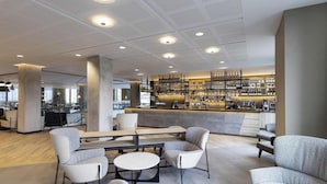 A modern bar area with seating, a bar counter, and a patterned rug. - Novotel Liverpool Paddington Village (Liverpool)