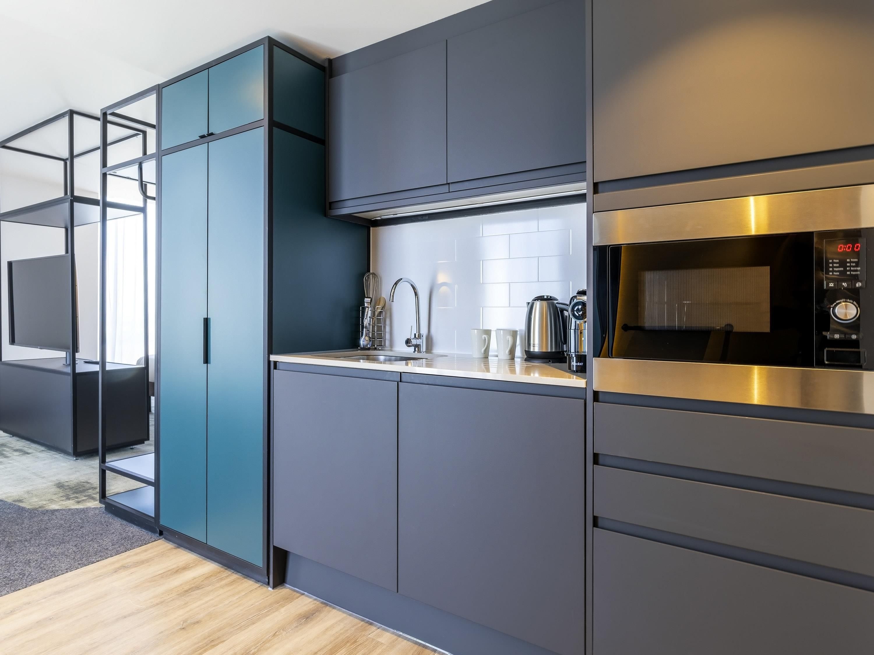 A modern kitchen with a built-in microwave, stainless steel appliances, and a minimalist design.