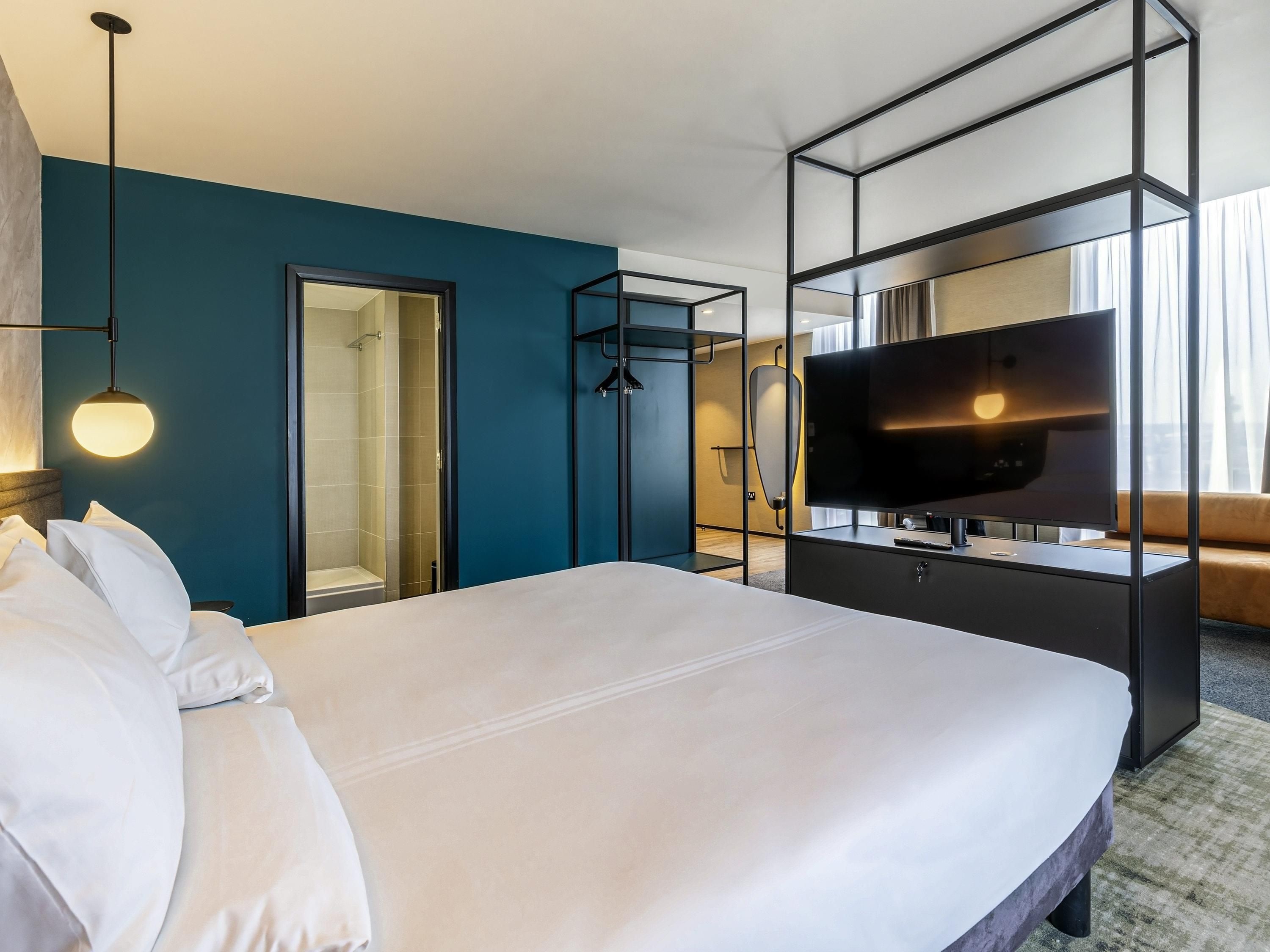 Habitación de hotel con cama, televisor, armario y baño.